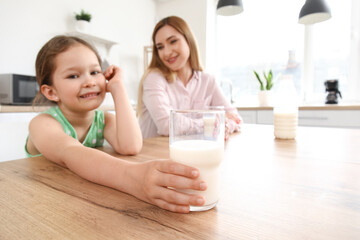 Little girl with her mother drinking milk in kitchen