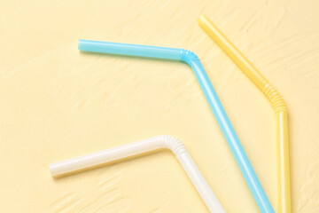 Different colorful straws on pale yellow background