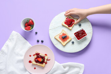 Female hand with delicious toasts, jam and berries on color background