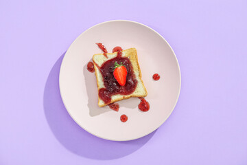 Plate of delicious toast with strawberry jam on lilac background