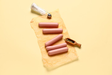 Baking paper with tasty thin sausages on beige background