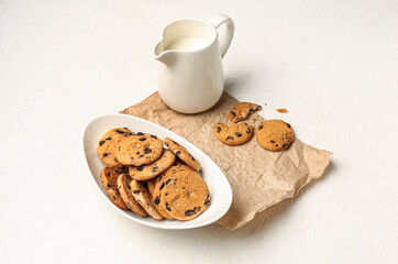 Bowl of cookies and jug with milk on white background
