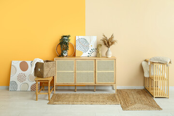 Stylish interior of living room with drawers, shelving unit, paintings and wicker rugs