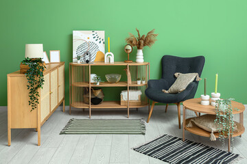 Stylish interior of living room with drawers, shelving unit, armchair and soft rugs