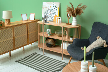 Stylish interior of living room with drawers, shelving unit, armchair and soft rug