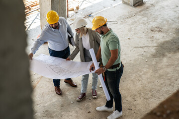 A female architect and construction manager work together on-site, discussing blueprints and coordinating to bring their project to life. - 615609716