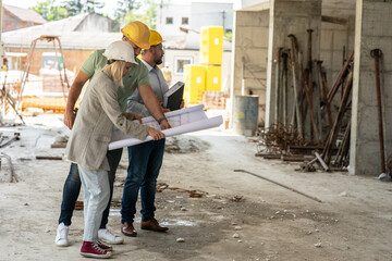 A female architect and construction manager work together on-site, discussing blueprints and coordinating to bring their project to life.