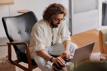 Focused male freelancer working on laptop while sitting in modern coworking. Remote work concept