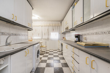 elongated kitchen with cabinets on each side of the walls, simil granite countertops, white cabinets with yellow pulls