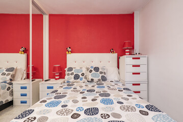 Frontal image of a bedroom with a double bed with an upholstered headboard, a striking bedspread