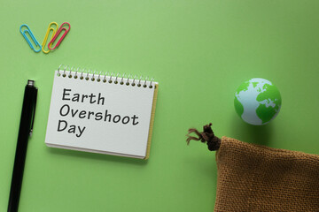 There is notebook with the word Earth Overshoot Day. It is as an eye-catching image.