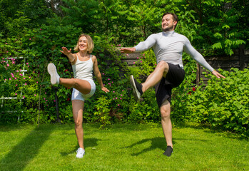 a couple performs physical exercises in nature.young man and woman do fitness athletics together in...