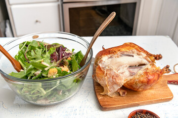 prepared Caesar salad in a glass bowl is on the kitchen table. Grilled chicken, crackers and ingredients.