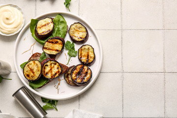 Toasts with delicious grilled eggplants and sauce on light background