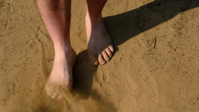 Close up and slow motion and close up while moving or shoveling bare male feet in the sand or dry dirt in sunny spot.