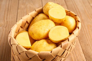 Wicker basket with raw baby potatoes on wooden background