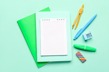 Notebooks with different stationery on turquoise background
