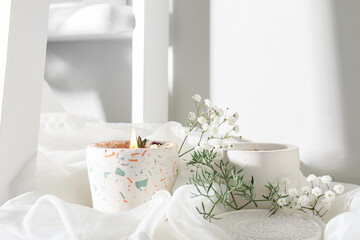 Gypsophila flowers and burning candle on table in room, closeup