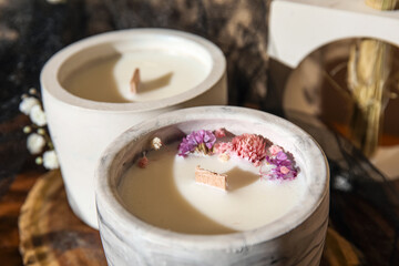 Holders with candles and flowers on table in room, closeup