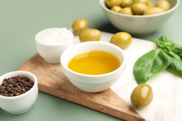 Bowl with fresh olive oil on green background