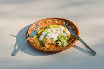 Savor the authentic Mexican flavor of green enchiladas served on a plate with silverware