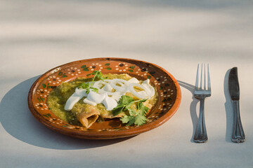 Savor the authentic Mexican flavor of green enchiladas served on a plate with silverware