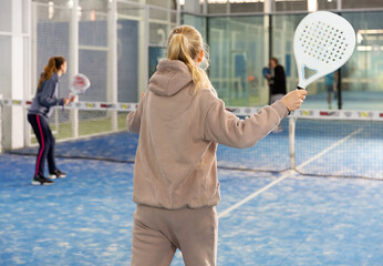 Portrait of a confident European woman engaged in a popular sport padel with a racket indoors