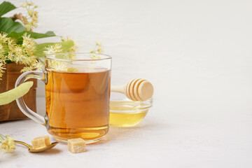 Glass cup of linden tea and bowl with honey on white background