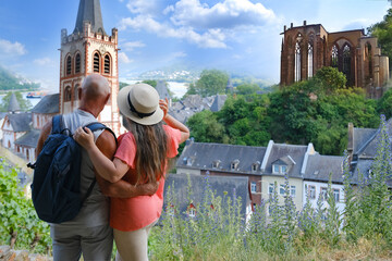 happy tourists couple stand over medieval German Bacharach city, woman and man with backpack look...