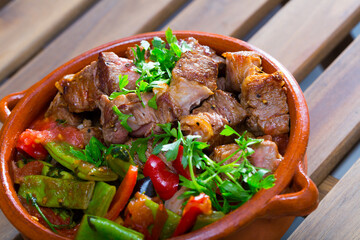 National Bulgarian dish Gyuvech - baked meat with assorted vegetables and greens traditionally served in earthenware pot - obrazy, fototapety, plakaty