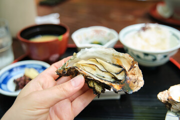 Close up of european tourist eating traditional oyster set in Miyajima, Hiroshima, Japan.