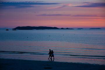 Couple qui se promène sur une plage bretonne au coucher du soleil
