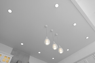 Ceiling with modern lamps in stylish kitchen, low angle view