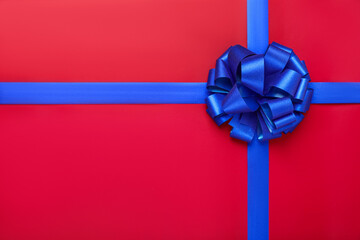 Blue ribbons with bow on red background, top view