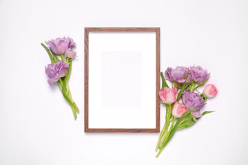 Empty photo frame and beautiful tulip flowers on white background, flat lay. Mockup for design