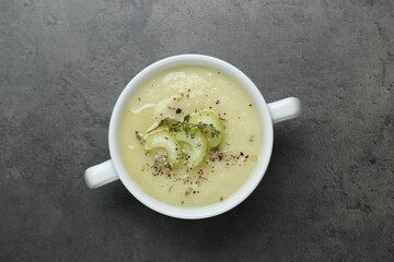 Bowl of delicious celery soup on gray table, top view