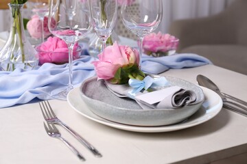 Stylish table setting with beautiful peonies, napkin and blank card indoors