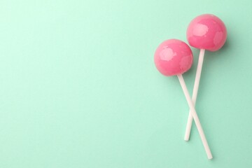 Tasty lollipops on turquoise background, flat lay. Space for text