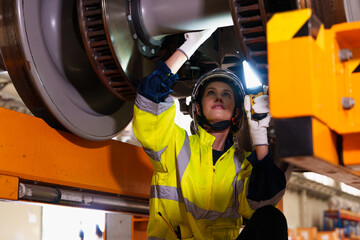 Railway technician engineer woman holds a light stick to check and fix the problem under an...