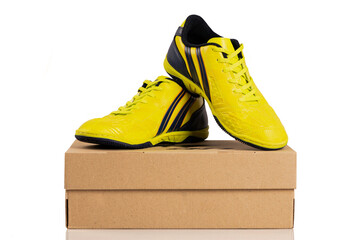 Pair of yellow shoes on brown paper box on white background. Football boots. soccer boots