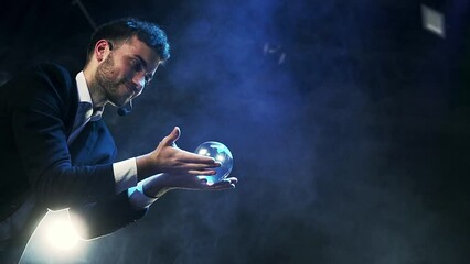 Slow motion shot of an illusionist holding a clear ball in his hands ready to perform