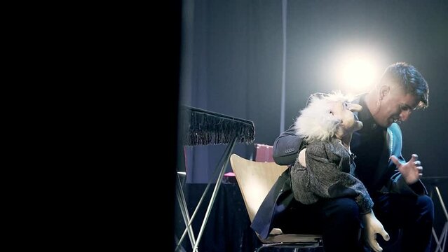 Backstage shot of a ventriloquist and puppet performing on stage with a spotlight 