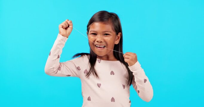 Dental, child with smile and floss in studio, morning routine for clean mouth, growth and happiness. Teeth, wellness and face of happy girl on blue background flossing, cleaning and care for children