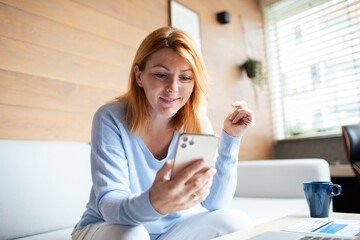 Mid adult woman using a smart phone at home