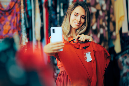Shopping Woman Taking a Selfie with a New Red Blouse. Cheerful customer having fun on a shopping spree
