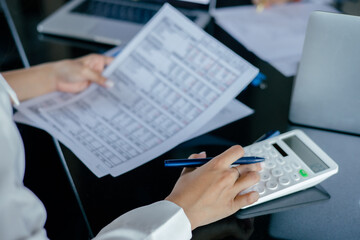 Business woman using a calculator to calculate the numbers on his desk in a office.