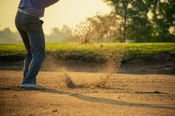Golfer's legs in the bunker amid the warm sunlight in the morning There is a golf ball and sand...