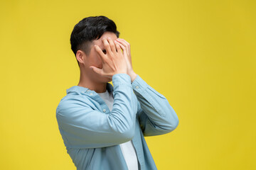 Young handsome holding his head looking desperate isolated on yellow background