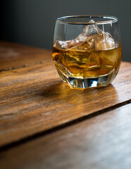 Glass of whiskey with ice on a wooden table