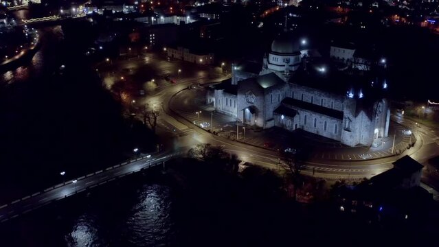 Galway cathedral and city lights at night.
Aerial shot reveals the Galway Cathedral and The Salmon Weir Bridge in a captivating panorama